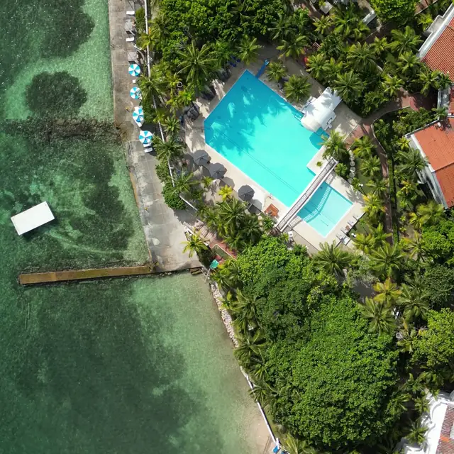 Aerial view of a resort pool, beach and pier over turquoise water near Cartagena